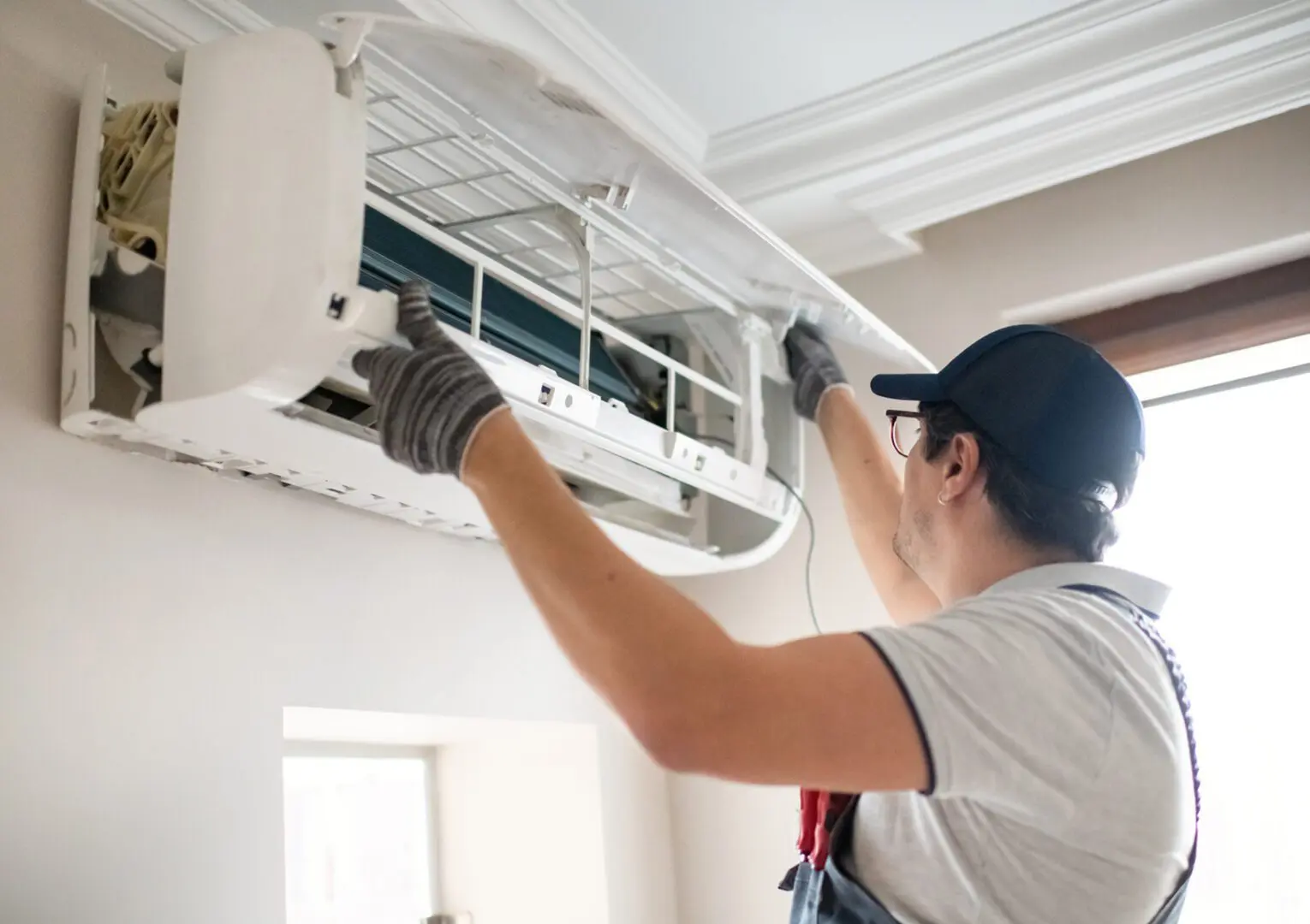 Technician repairing wall-mounted air conditioner unit.