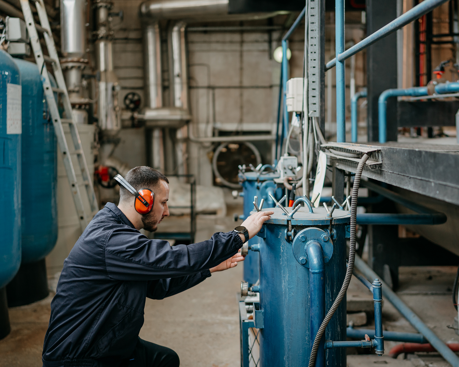 Worker inspecting machinery at industrial facility.
