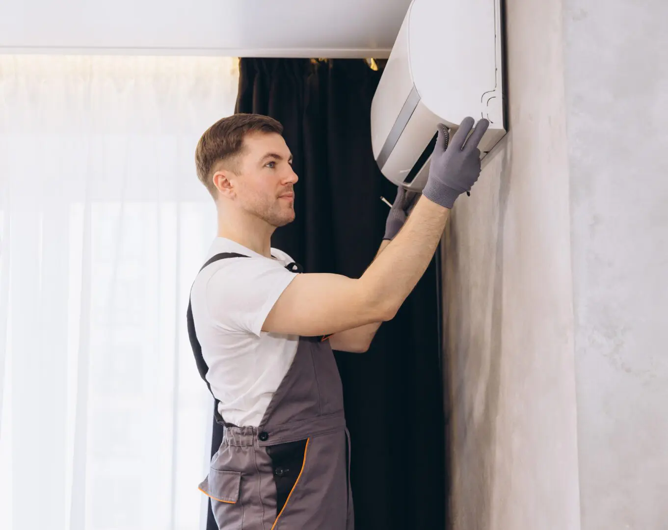 Technician installing air conditioning unit indoors.