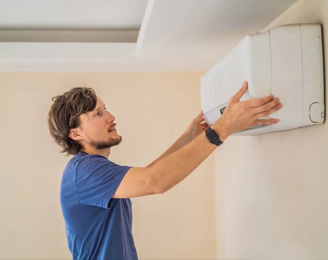 Person adjusting wall-mounted air conditioner unit.