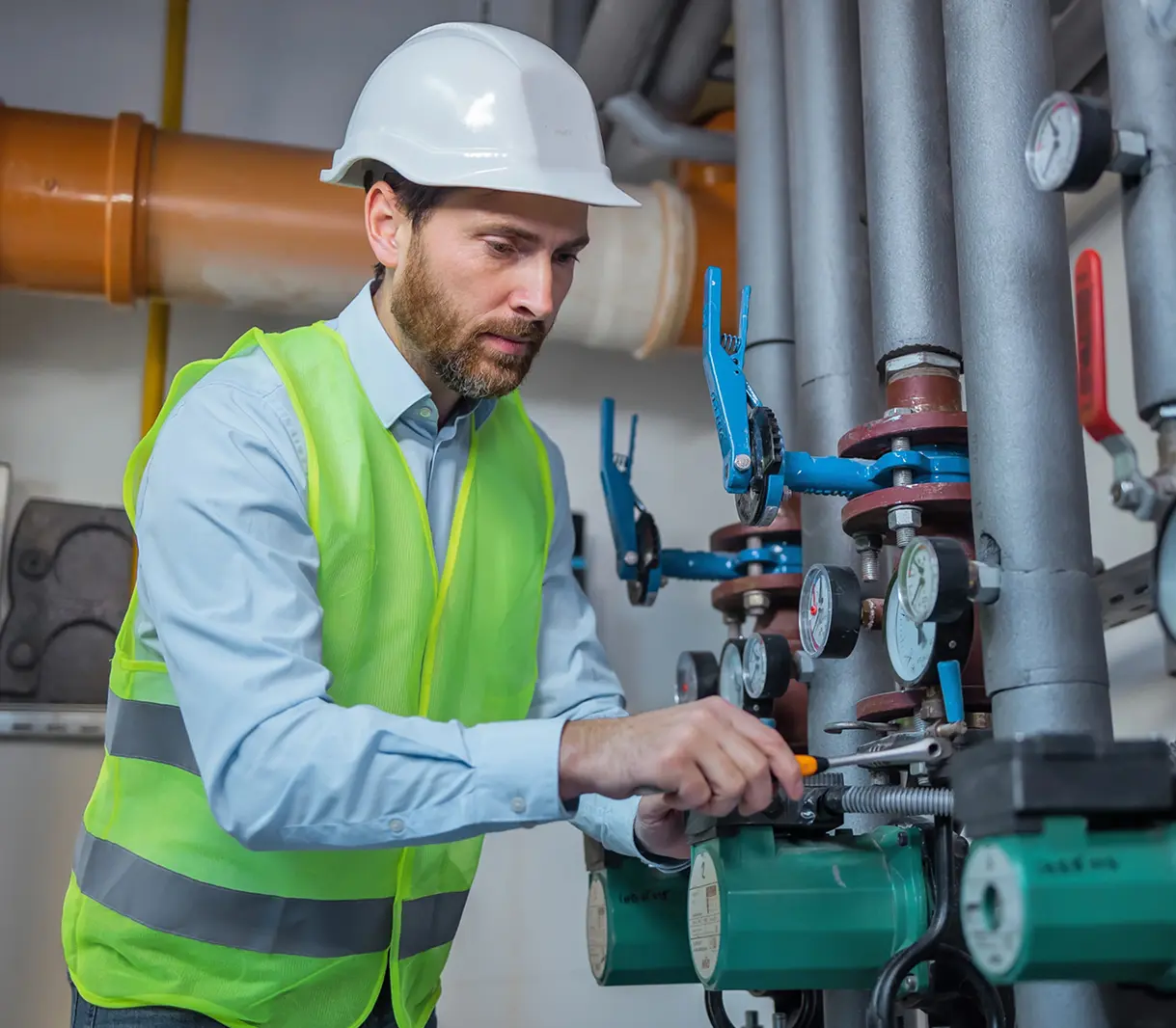 Worker adjusting industrial pipes and gauges.