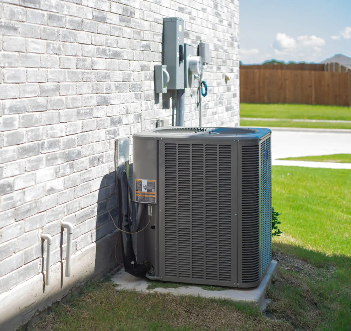 Outdoor air conditioning unit beside brick wall.