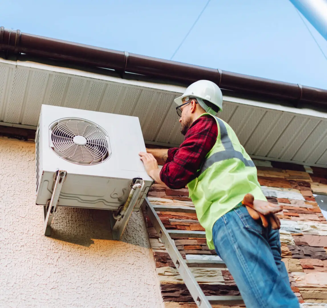 Worker inspecting outdoor air conditioning unit.
