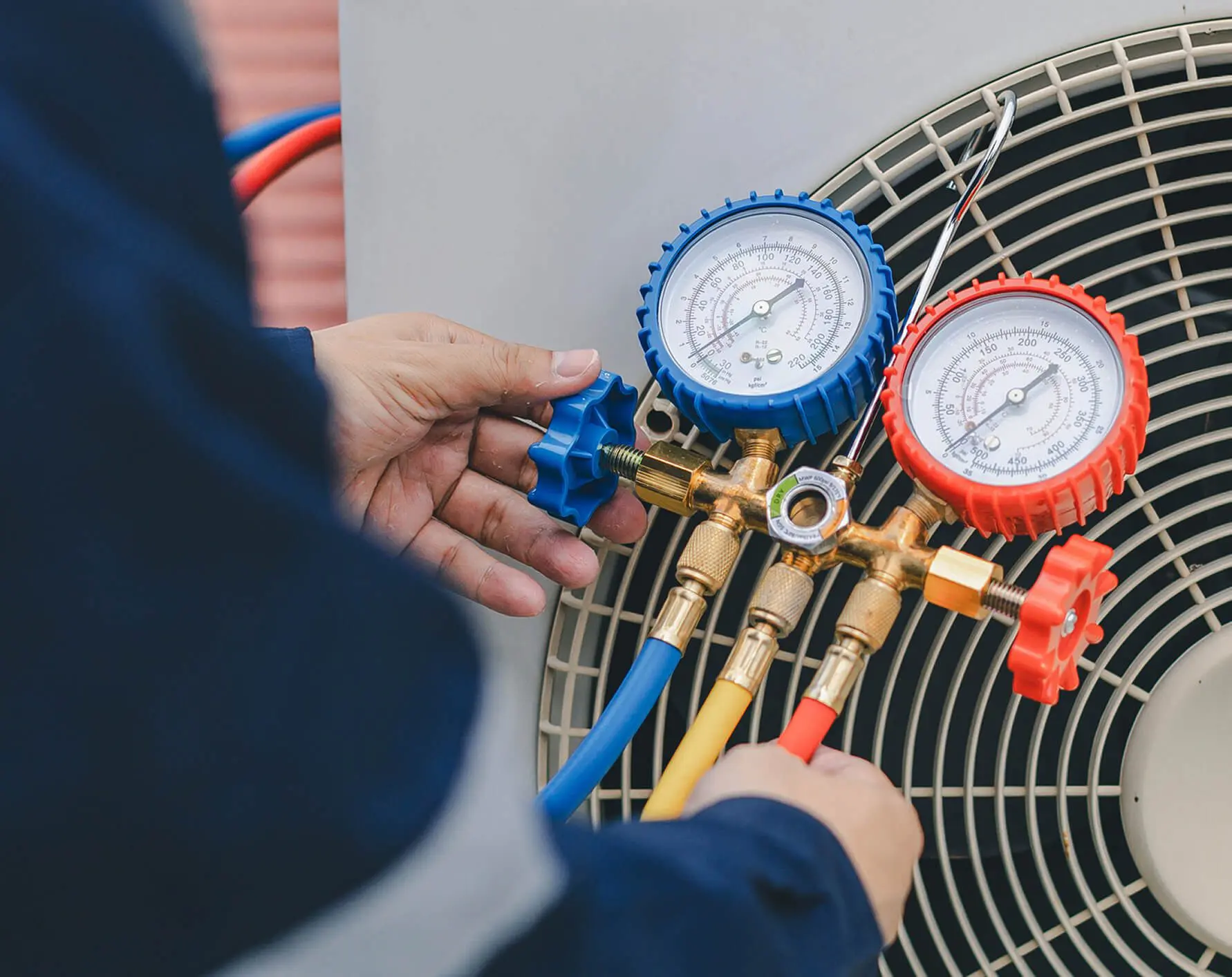 Technician adjusting HVAC system pressure gauges.