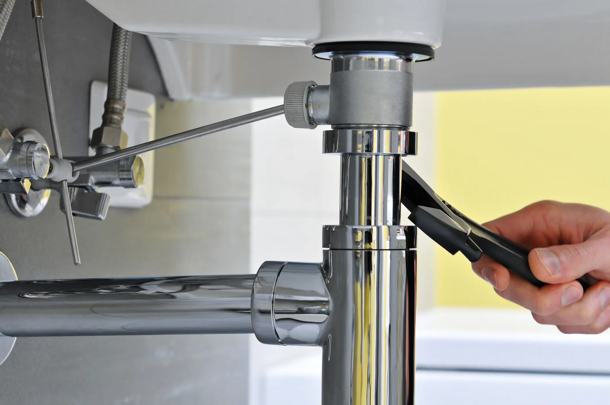 Plumber tightening chrome sink drain with pliers