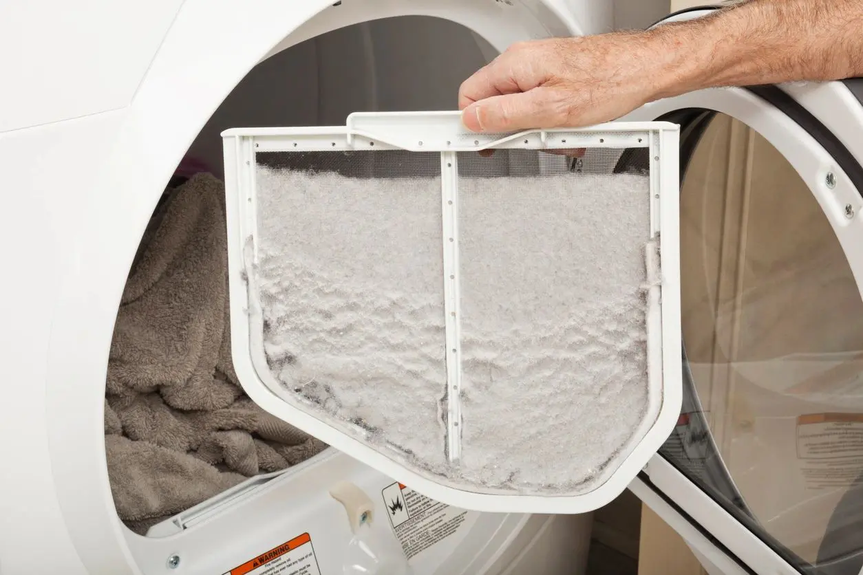 Hand removing lint-filled dryer filter