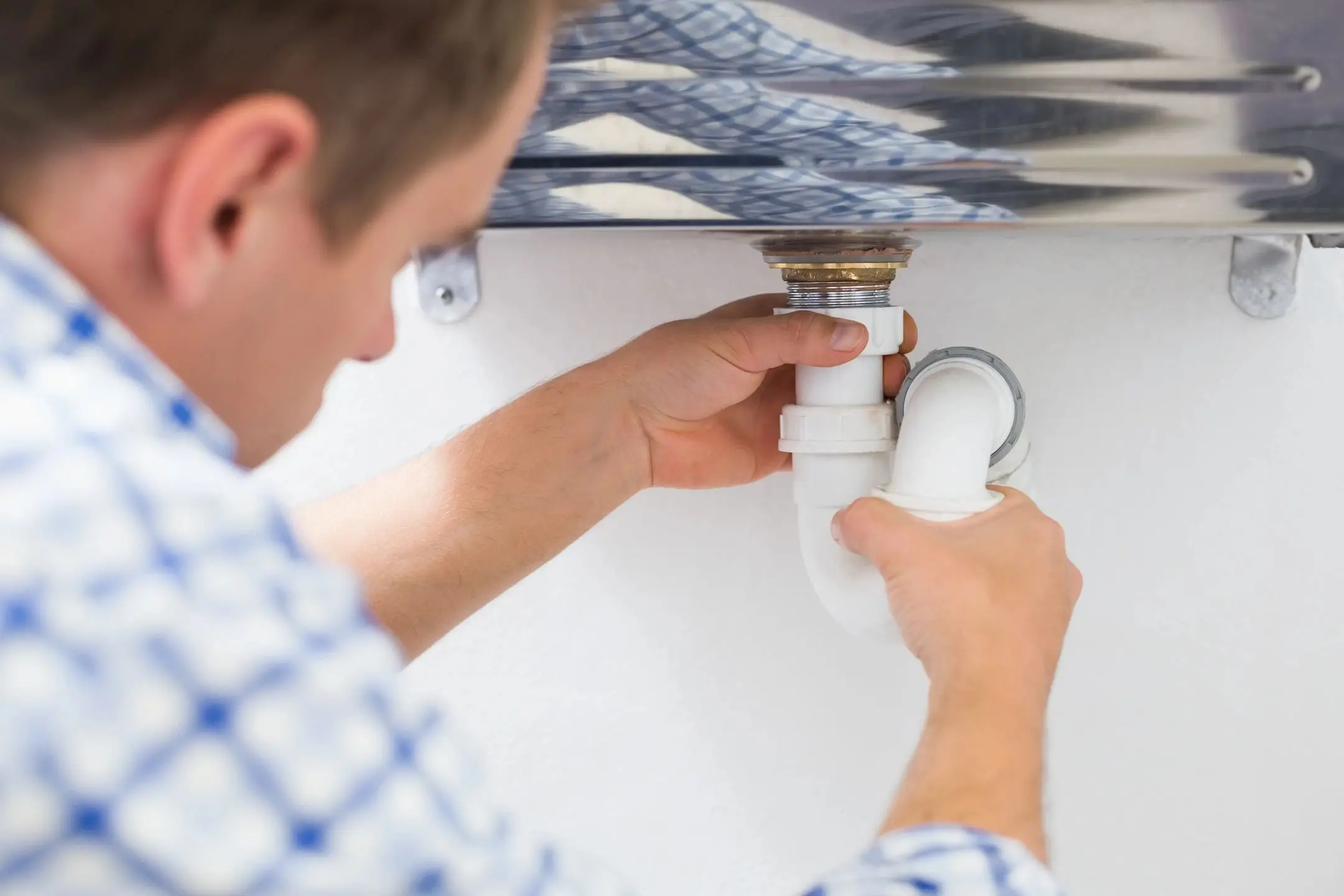 Plumber installing P-trap under kitchen sink