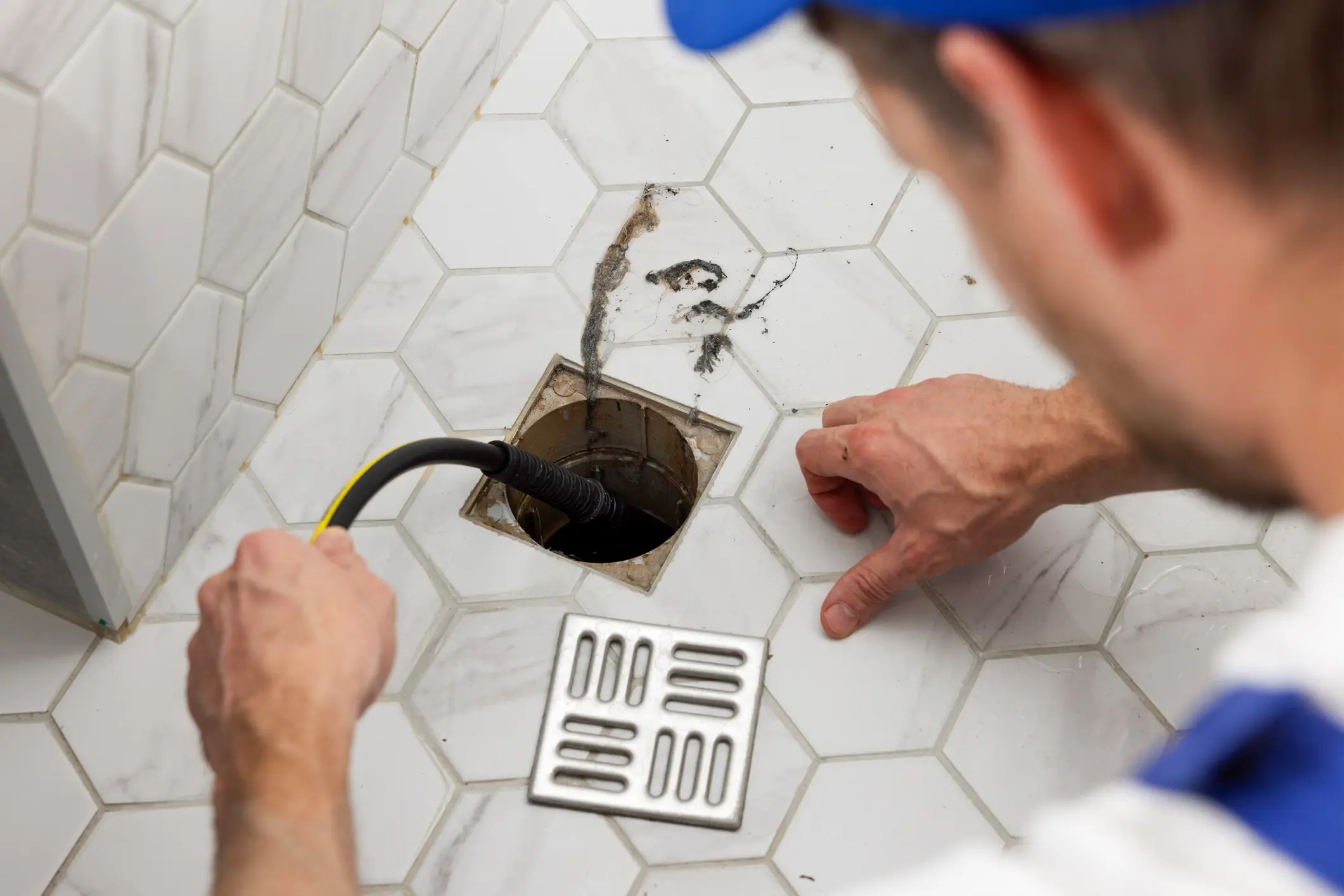 Plumber inspecting shower drain with snake