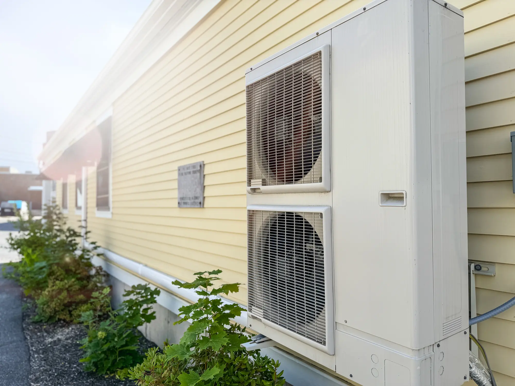 Outdoor air conditioning unit on yellow siding