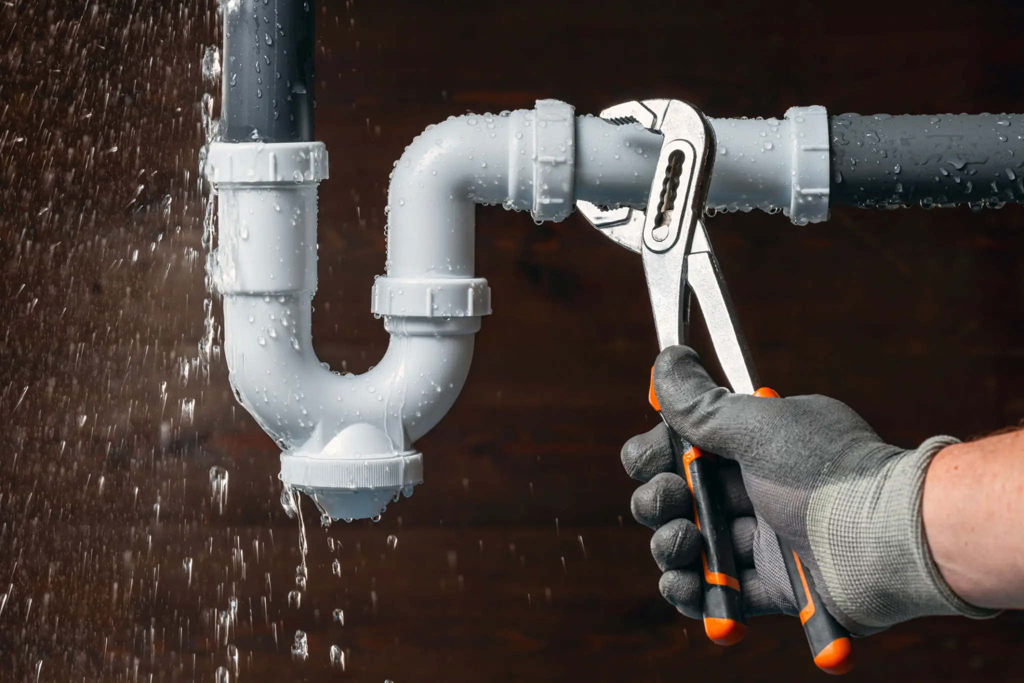 Gloved hand tightening leaking gray pipe