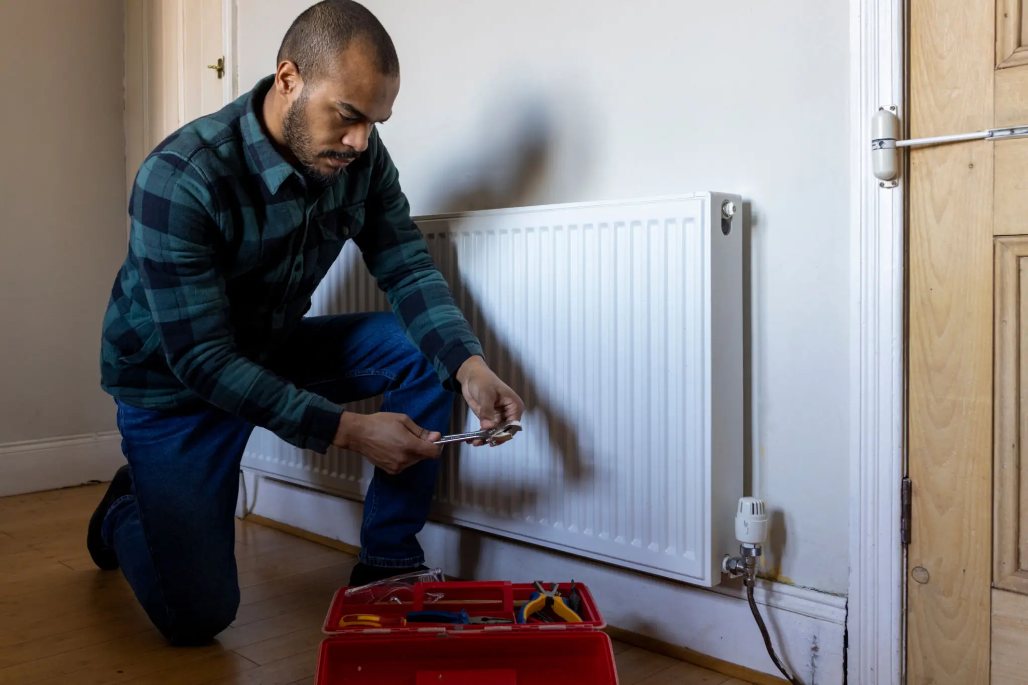 Technician repairing white home radiator with toolbox
