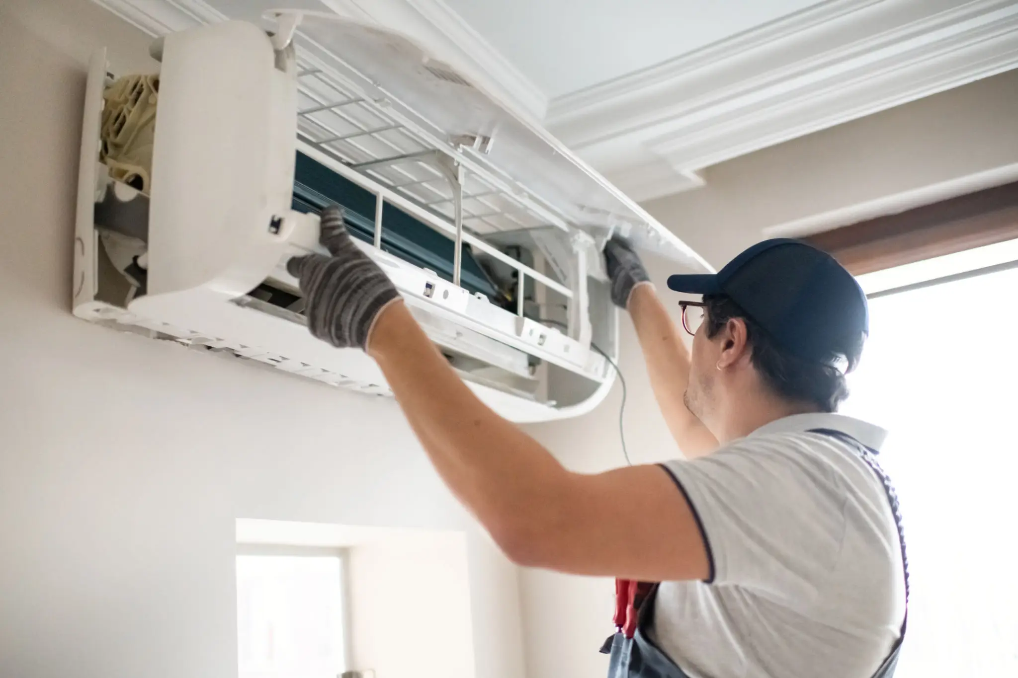 Technician servicing wall-mounted air conditioner indoors