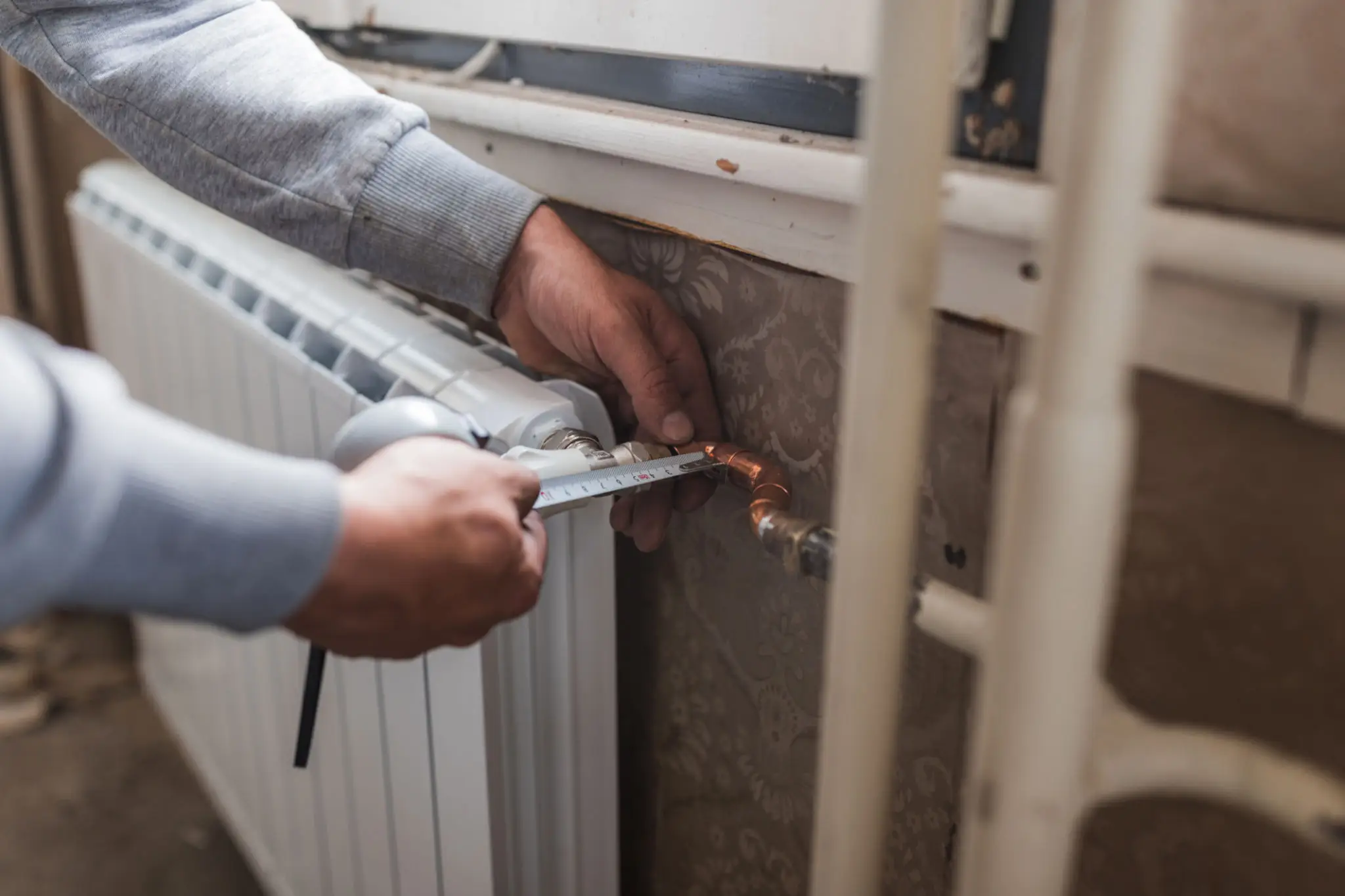 Plumber tightening radiator valve with wrench