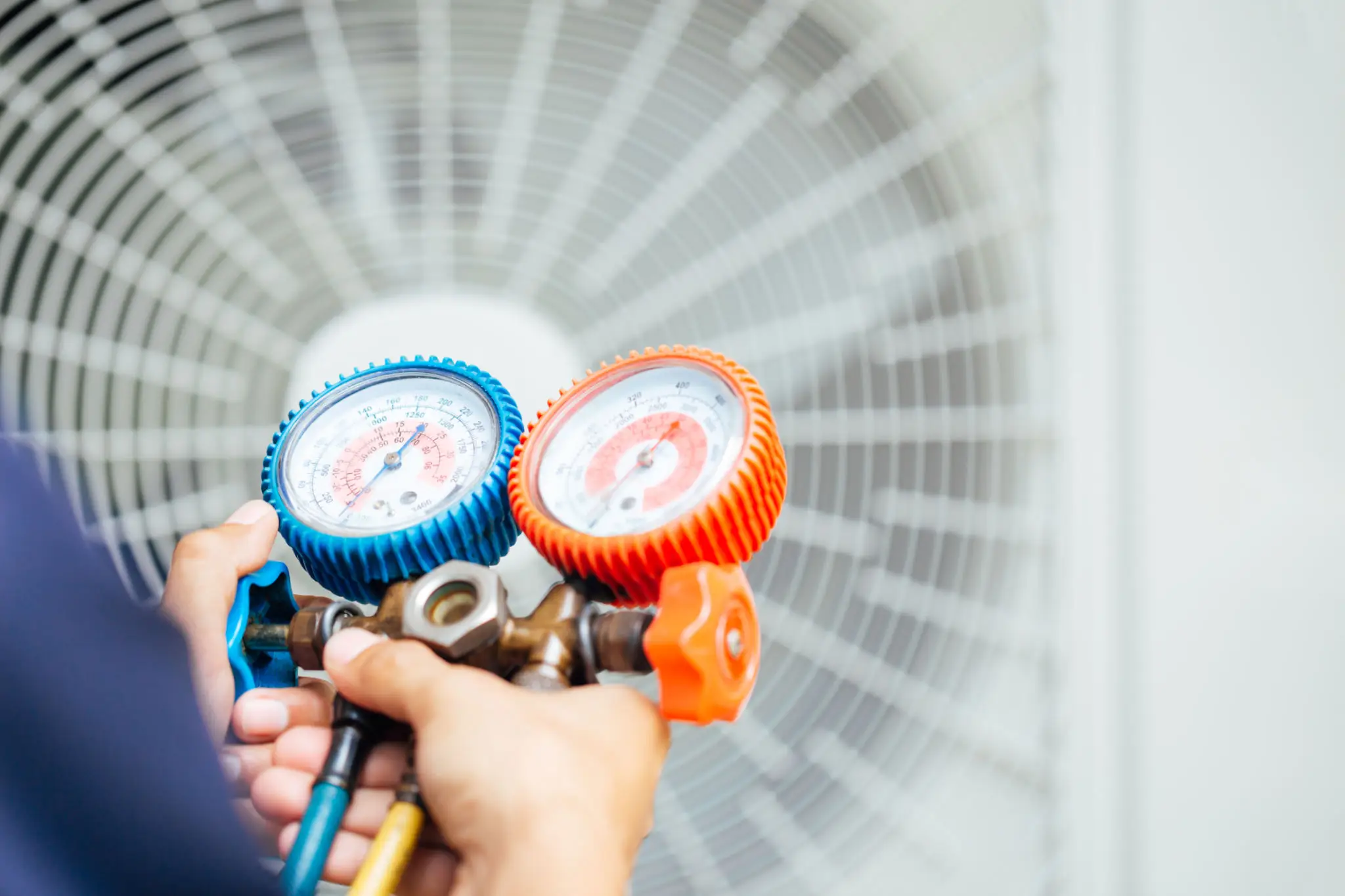 Technician holding AC manifold gauges near condenser