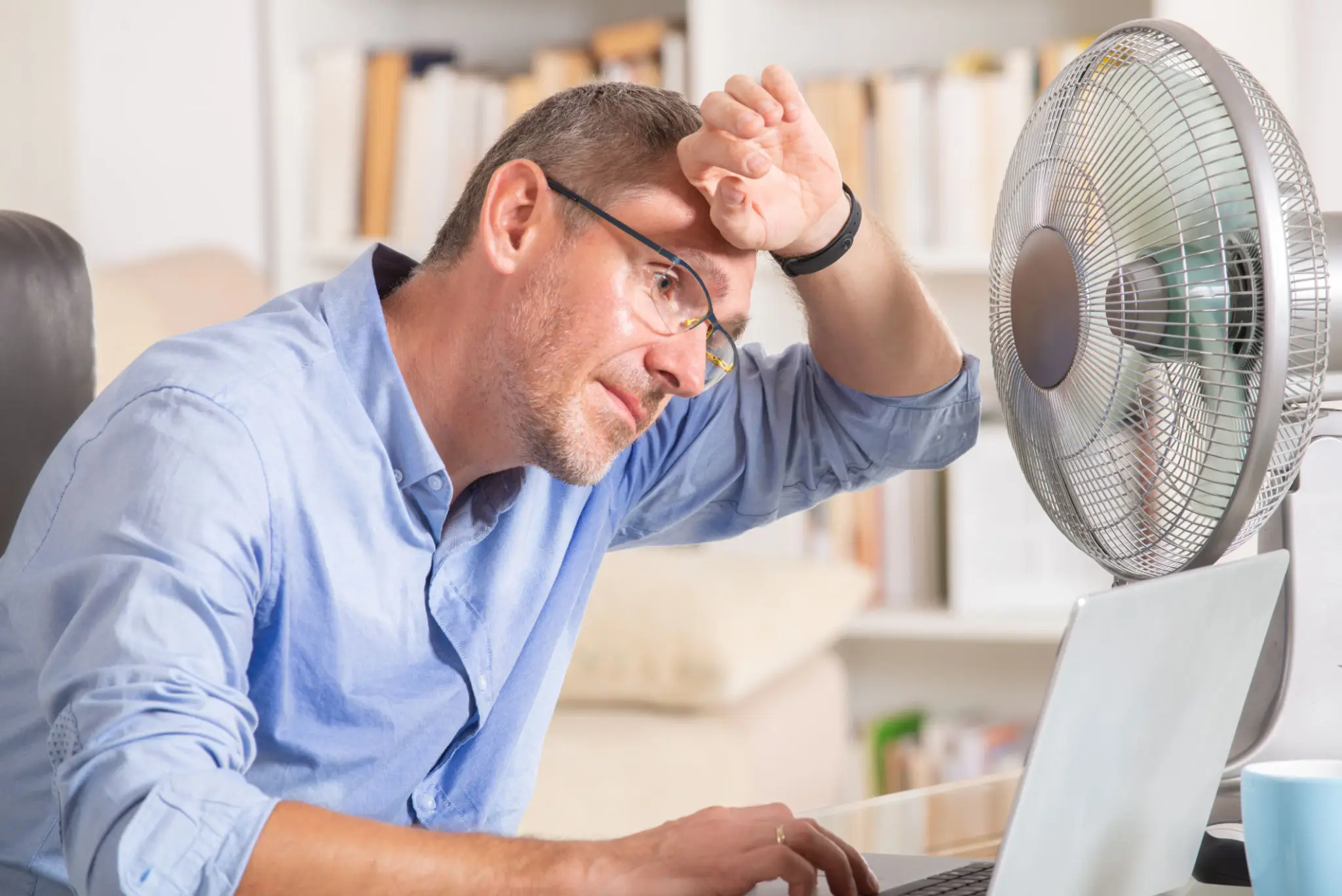Man cooling off with fan while working