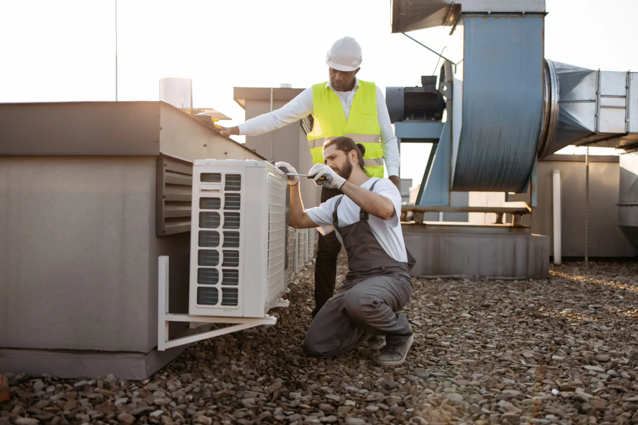 Two technicians repairing rooftop air conditioning unit
