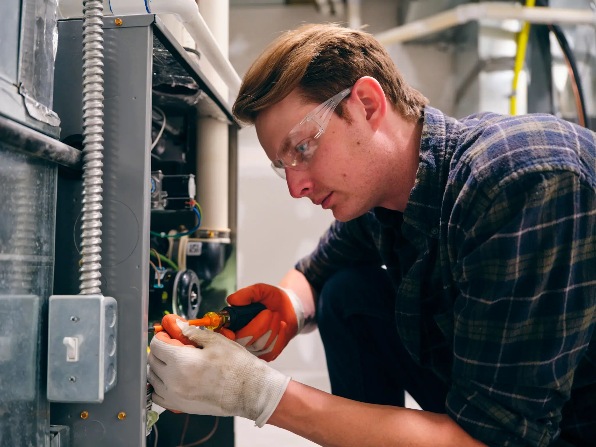 HVAC technician repairing furnace wearing safety glasses