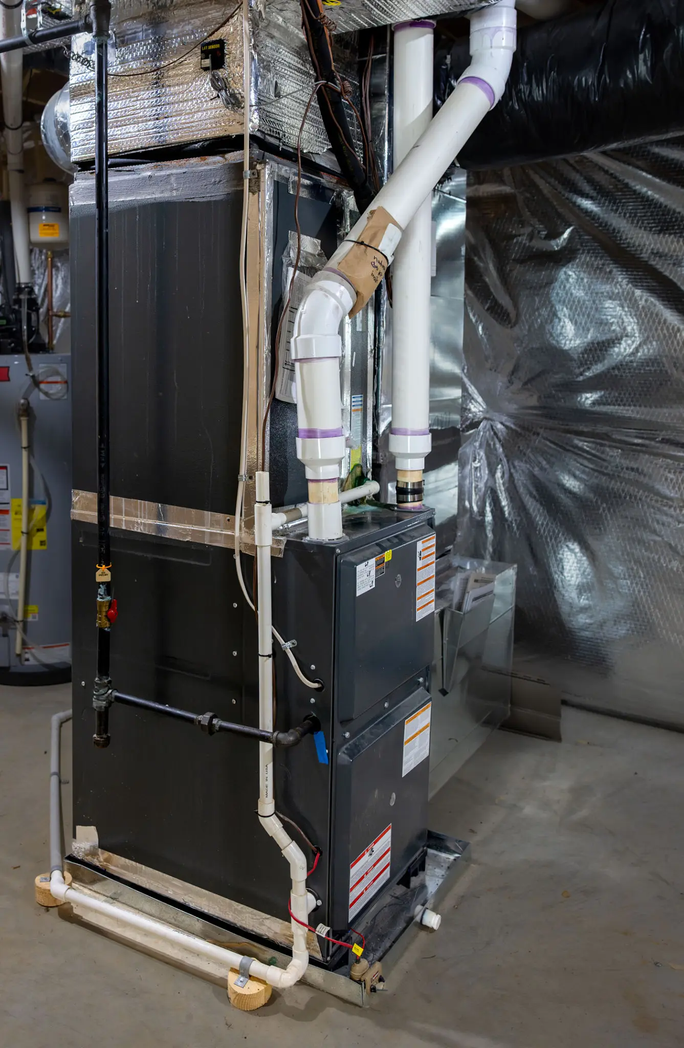Basement HVAC furnace with PVC drain pipes