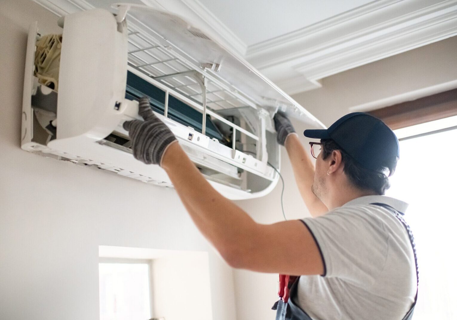 Technician repairing wall-mounted air conditioner unit.
