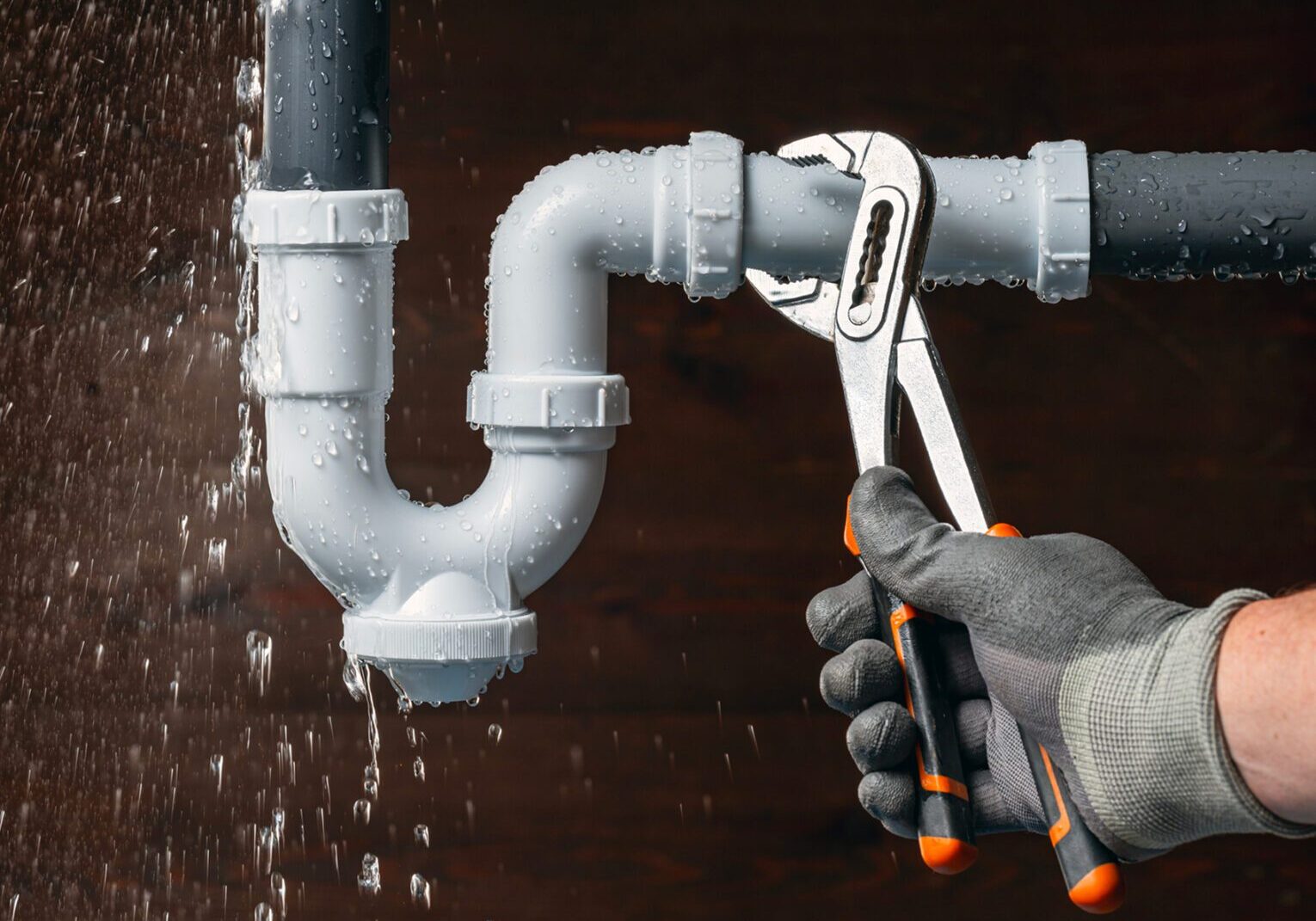 Plumber fixing leaking pipe with wrench.