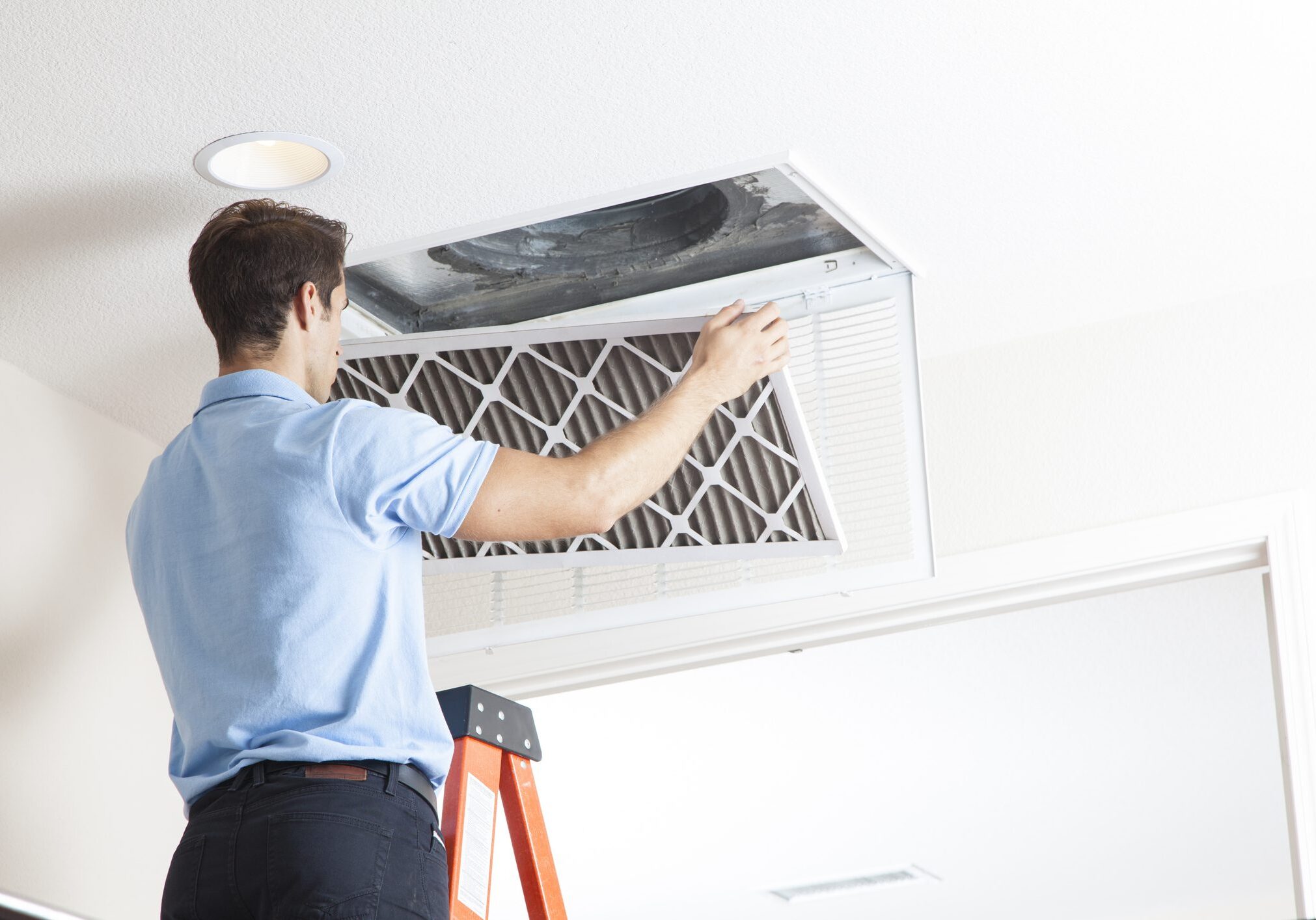 Technician replacing ceiling HVAC air filter